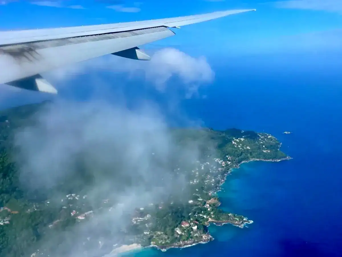 Vue aérienne des îles Seychelles depuis l'avion, avec la mer turquoise et la côte verdoyante en dessous, idéale pour des vacances tropicales.