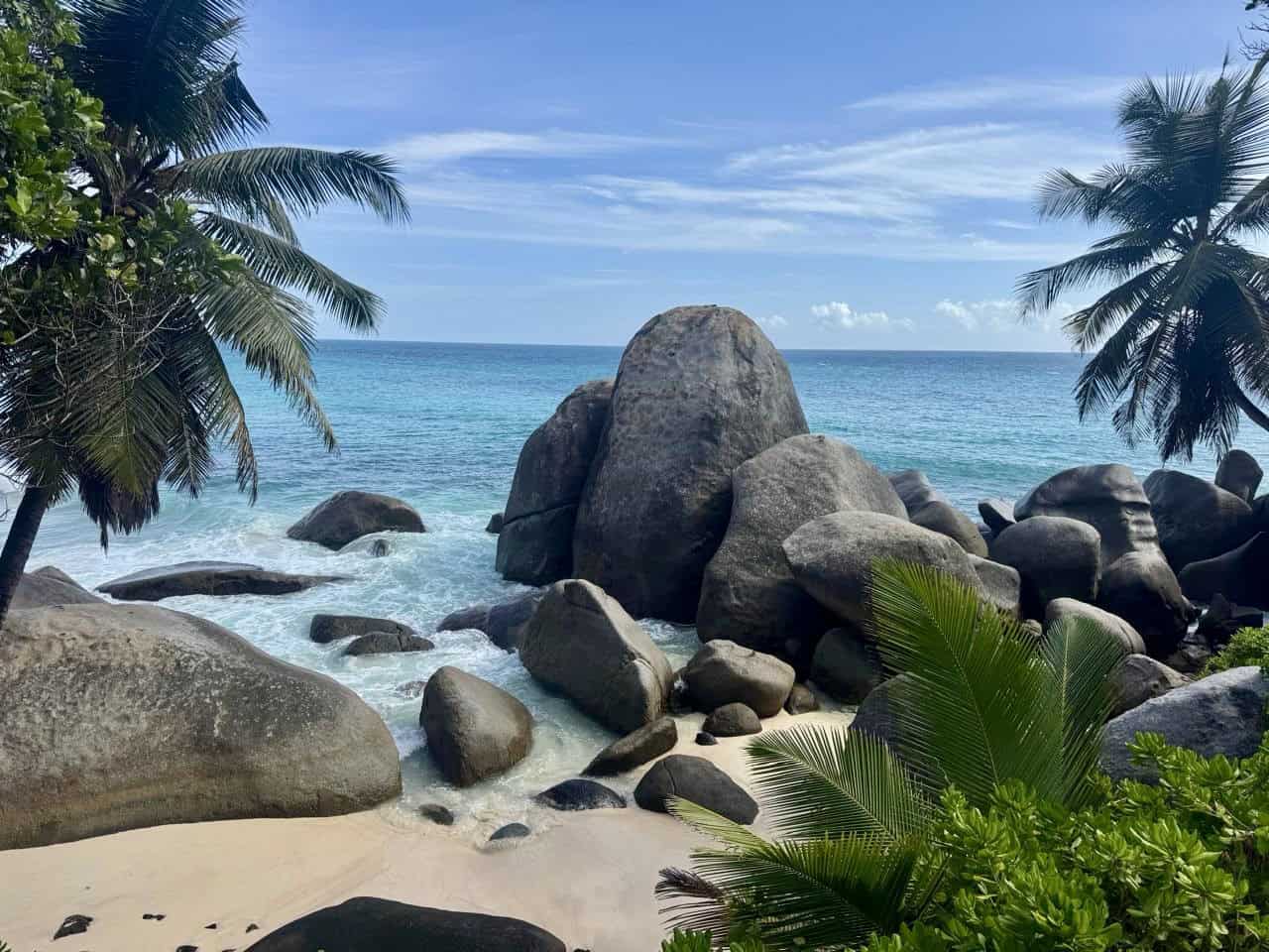 Paysage de plage aux rochers, cocotiers et mer turquoise à Seychelles.