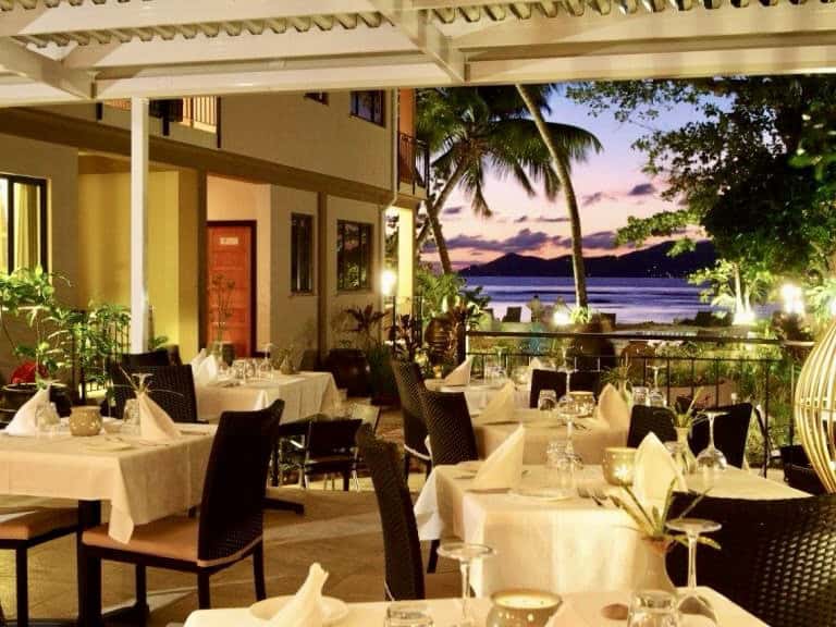 Salle à manger en plein air au coucher du soleil près de la plage aux Seychelles.