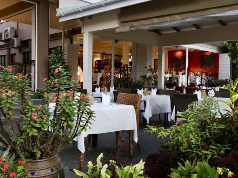 Fleurs tropicales et terrasse de restaurant élégante à Mahé, Seychelles, ambiance chaleureuse et décor raffinée.